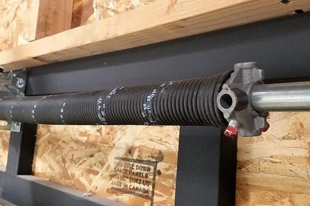 Close-up of an installed garage door torsion spring above the door opening