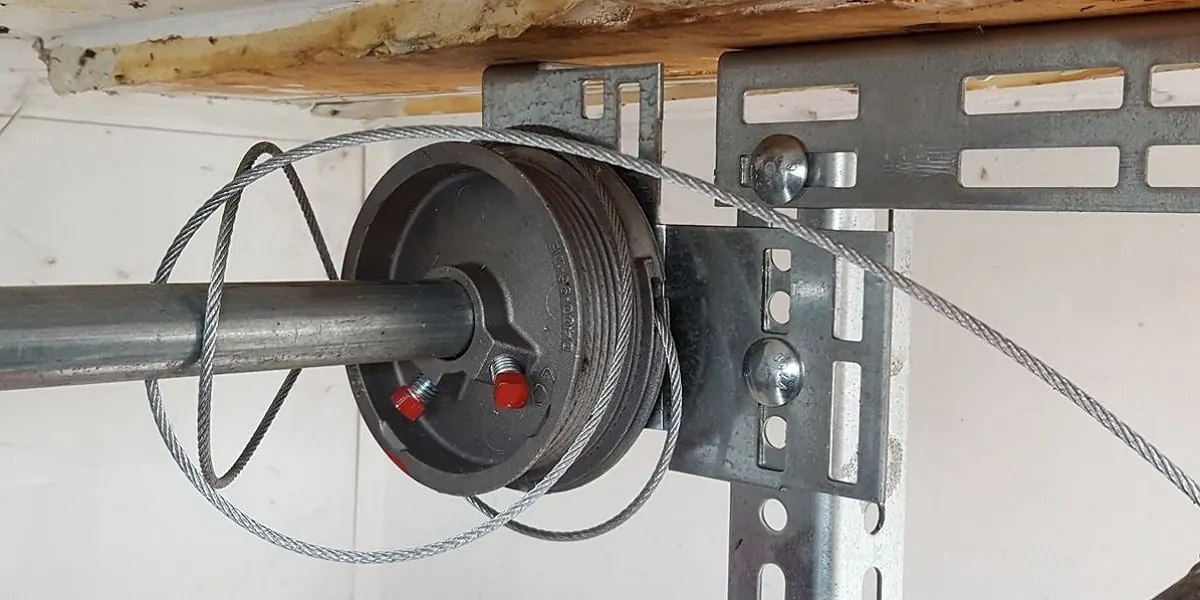 Close-up of a garage door cable drum with steel lifting cable on the torsion shaft
